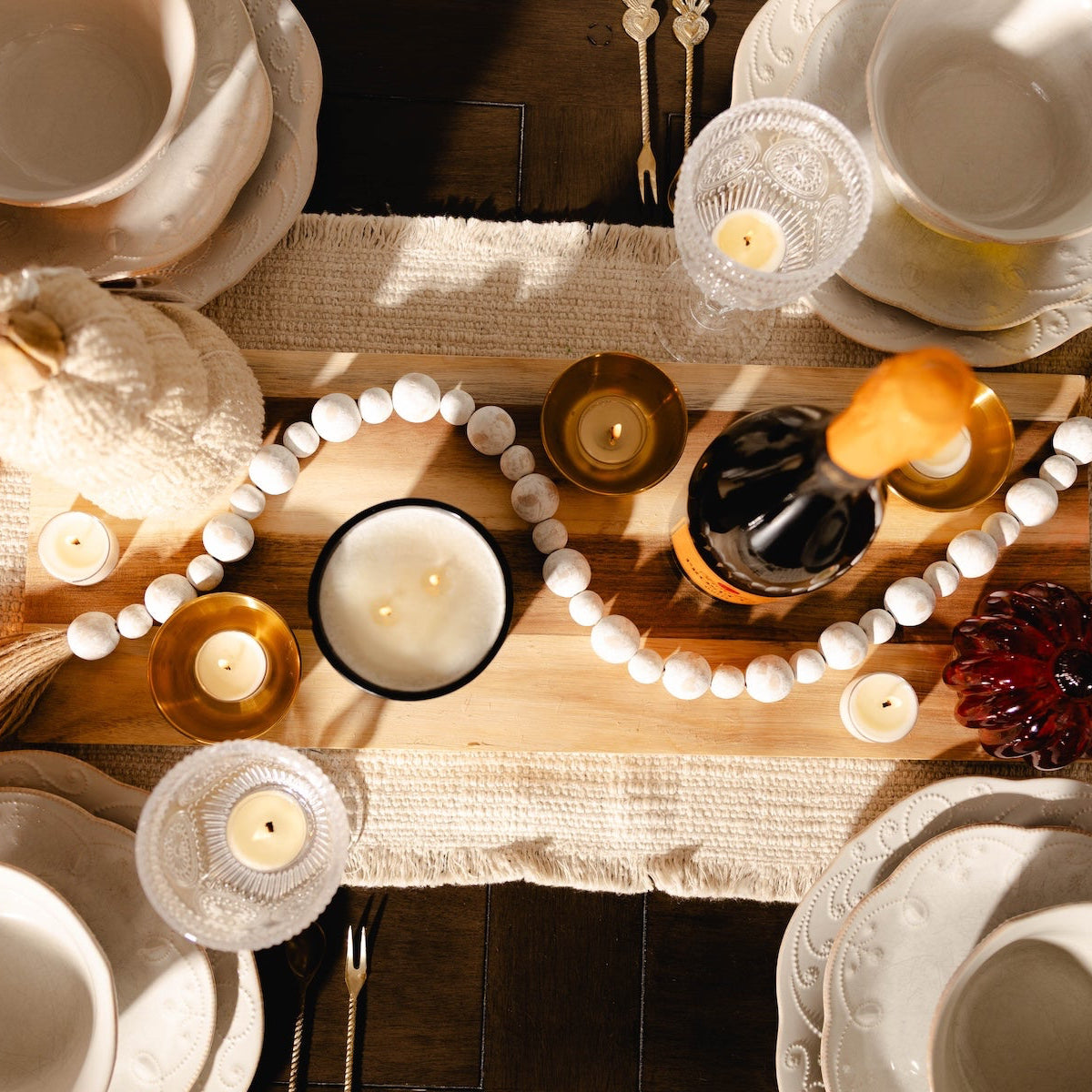 Dining table setting with plates, candles, and decorative items on a textured tablecloth.