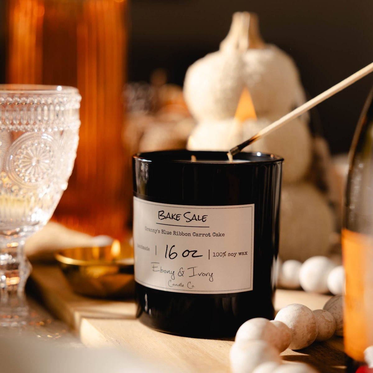 Black candle labeled 'Bake Sale' on a table with decorative items