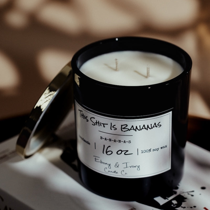 Black candle with a label on a book titled 'Yves Saint Laurent'. Canadas soy candle that smells like banana cream pie.