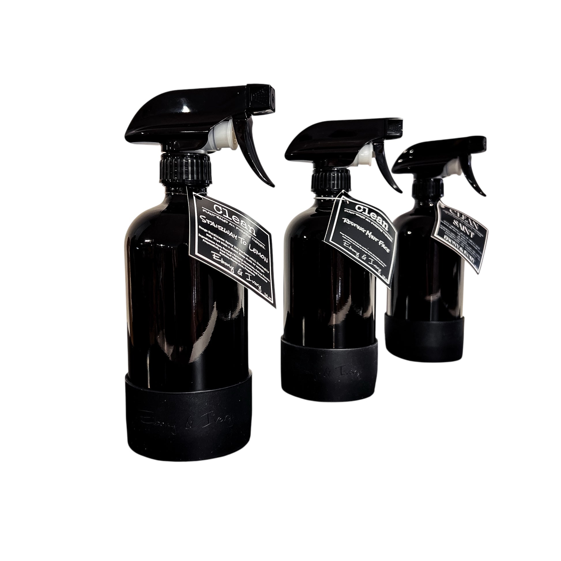 3 16oz black spray bottles of all purpose cleaner with black labels are lined up on a white background. The first one is named Stairway to Lemon, the second is Resting Mint Face, & the third is Saint. They're made by Ebony & Ivory Candle Co in Lethbridge, Alberta, Canada