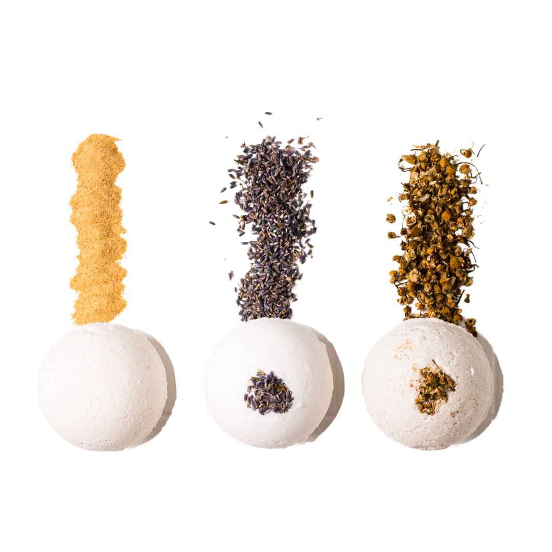 3 white bath bombs, one made with pumpkin powder, one made with lavender buds, and one made with chamomile buds, made by Ebony & Ivory Candle Co in Lethbridge, Alberta, Canada