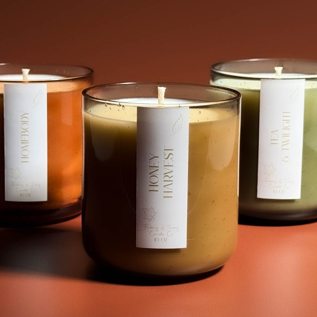 Three scented candles with labels on a warm brown background