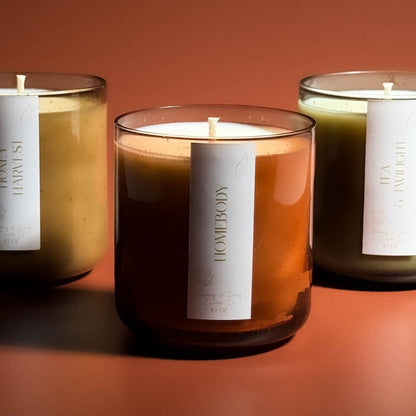 Three scented candles with labels on a warm-toned background