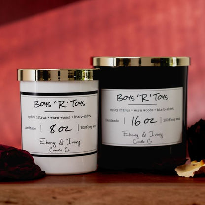 Two candles with labels on a wooden surface against a red background