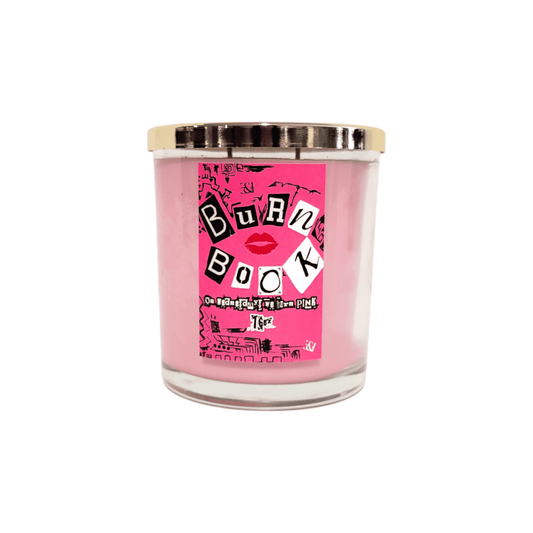 A clear 16oz jar soy candle with pink coloured wax, a gold lid, and a pink label named Burn Book, on a white background, made by Ebony & Ivory Candle Co in Lethbridge, Alberta, Canada
