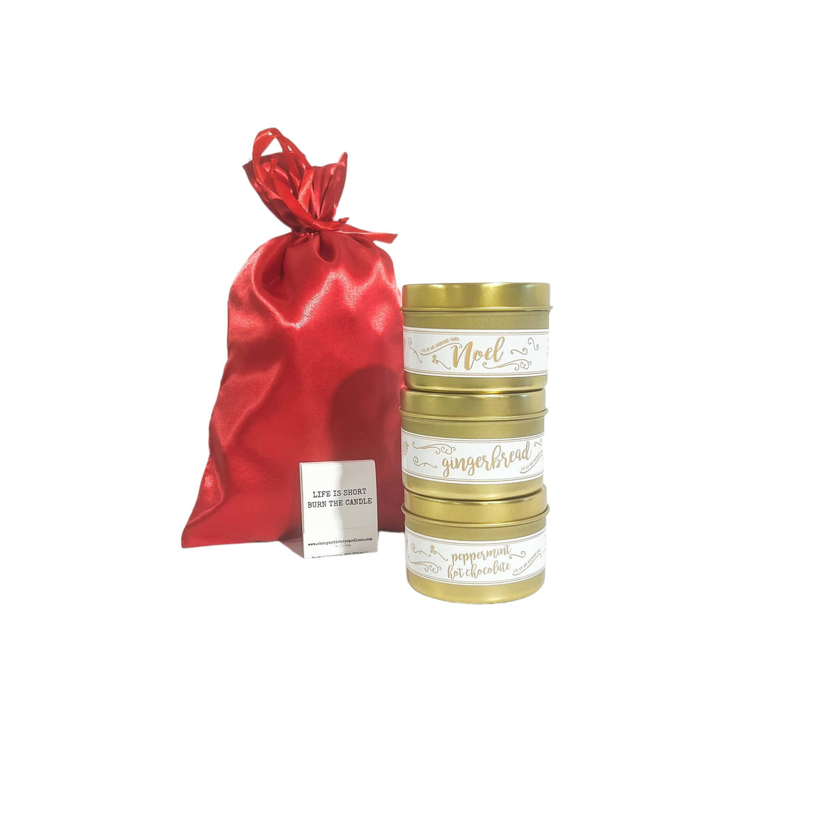 A stack of three gold 4oz soy christmas candles with a red satin bag and a book of matches.