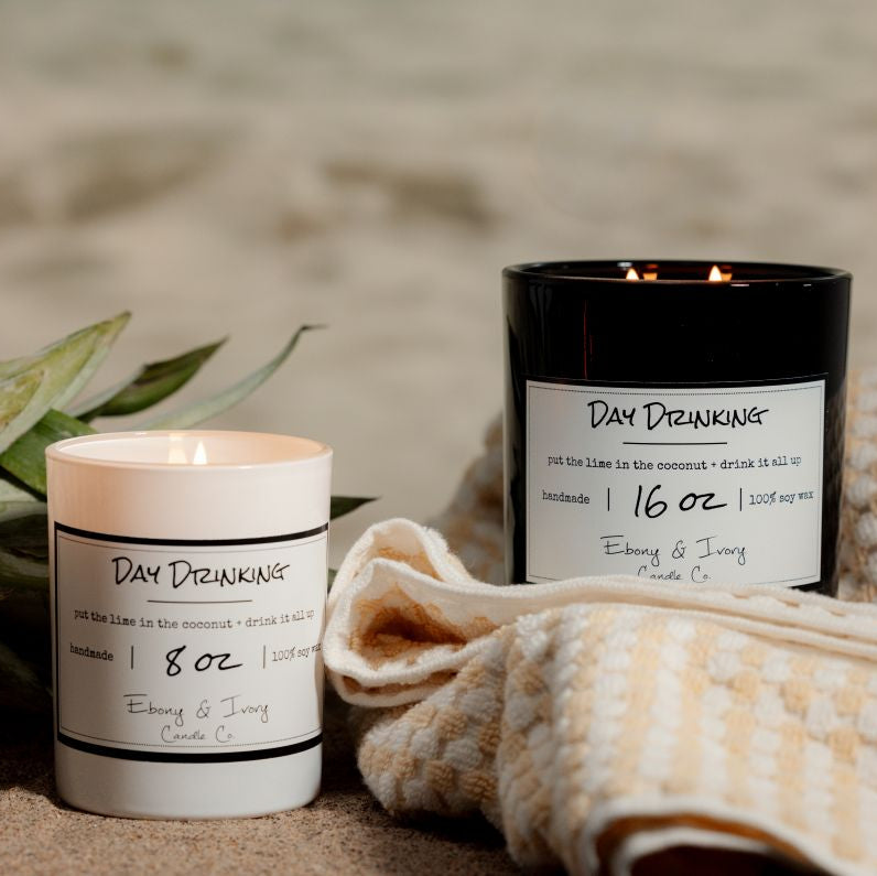 a white 8oz and a black 16oz soy candles sitting on the beach. Made in lethbridge alberta canada