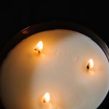 A top down view of a three wick, black 18oz jar coconut soy candle with a stamped imprint in the wax saying Debut on a black background, made by Ebony & Ivory Candle Co in Lethbridge, Alberta, Canada