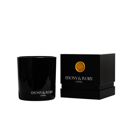 A black 18oz jar coconut soy candle with a white Ebony & Ivory on the front of it, next to a black box with a old seal label named Dolce, on a white background, made by Ebony & Ivory Candle Co in Lethbridge, Alberta, Canada