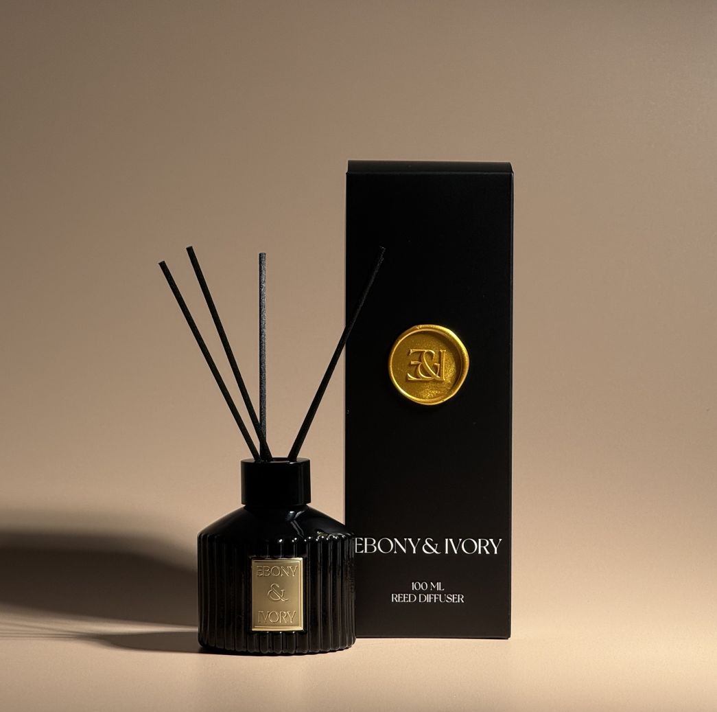 Black reed diffuser with decorative packaging on a beige background