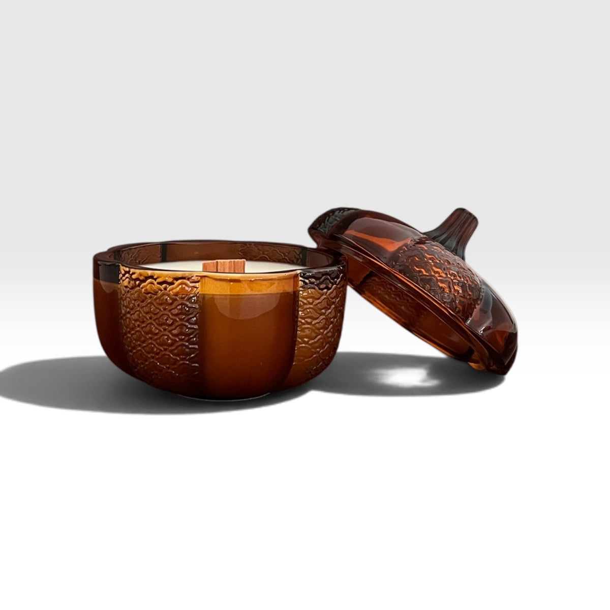 An 8oz soy wood wick soy candle in an amber heirloom pumpkin jar with the lid off.
