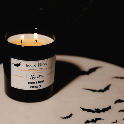 Black 16oz soy Candle with a label on a dark background. Hocus Pocus soy candle Canada. Fall season candle. 