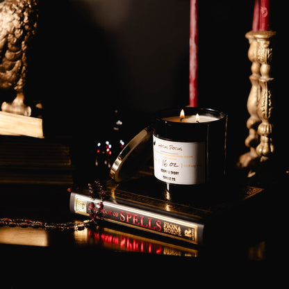 Black 16oz Soy candle with a label on books and a statue in a dark romantic setting. named "hocus pocus"