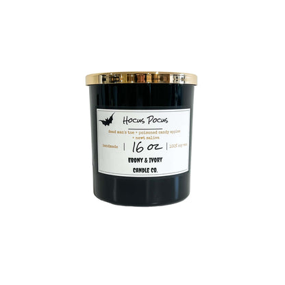 A black 16oz soy candle with a gold lid and a white label with a bat, named "hocus Pocus"