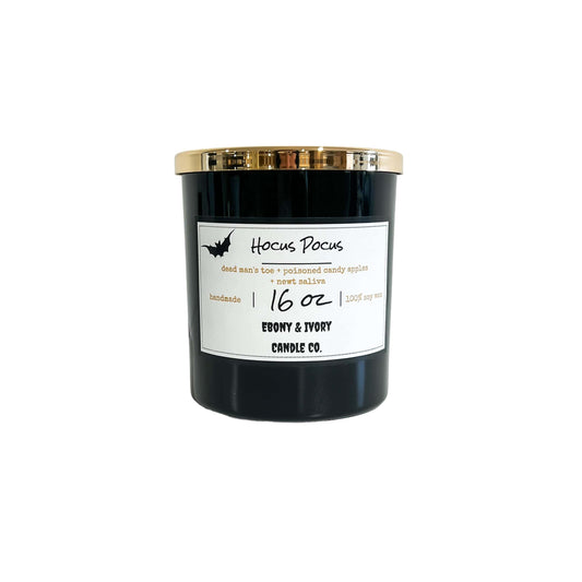A black 16oz soy candle with a gold lid and a white label with a bat, named "hocus Pocus"