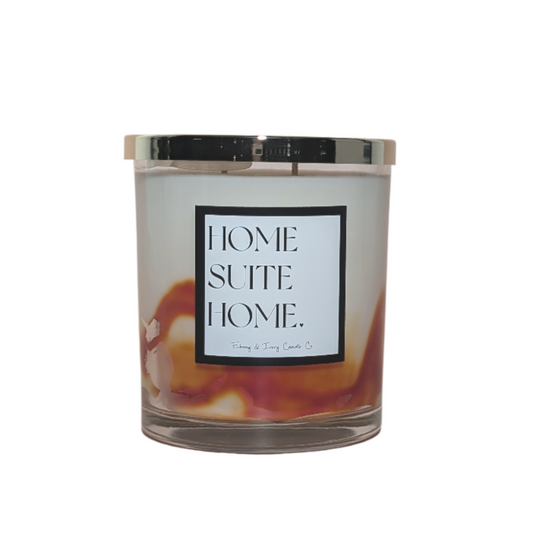 A clear 16oz jar soy candle with a gold lid and a white label named Home Suite Home. The wax is marbled with orange on the bottom. made by Ebony & Ivory Candle Co in Lethbridge, Alberta, Canada