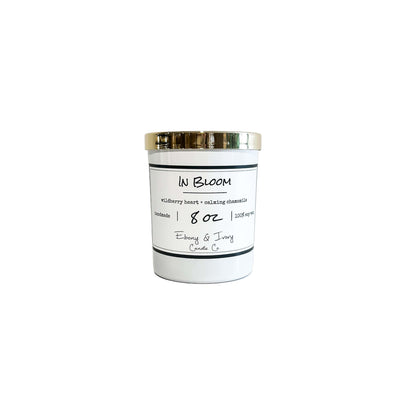 A white 8oz jar soy candle with a gold lid and a white label named In Bloom, on a white background, made by Ebony & Ivory Candle Co in Lethbridge, Alberta, Canada