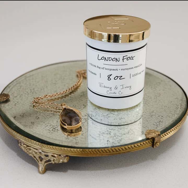 A white jar 8oz soy candle with a gold lid and a white label named London Fog, on a gold tray with a necklace beside it, made by Ebony & Ivory Candle Co in Lethbridge, Alberta, Canada