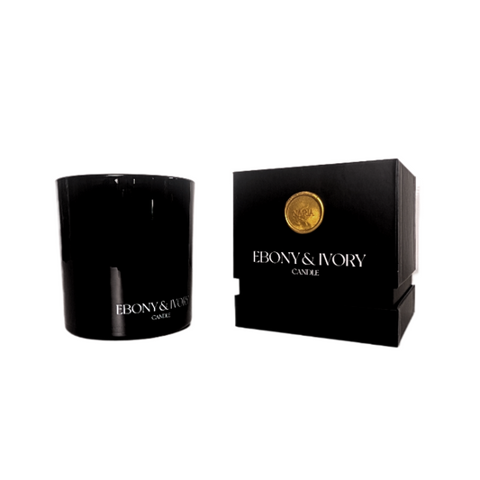 A black 18oz coconut soy candle on a white background next to a black box with a gold wax seal labelled Naria