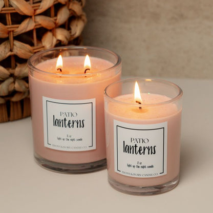 A clear jar 8oz and a clear jar 16oz soy candle labelled Patio Lanterns sitting on a table with a wicker basket. Made in Lethbridge Alberta Canada