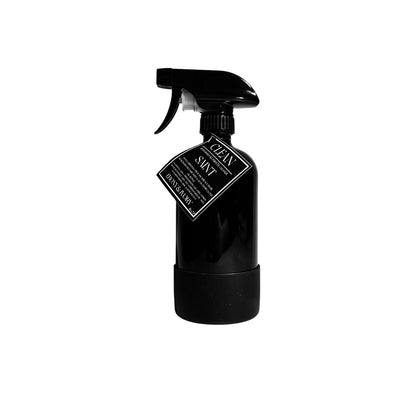 A 16oz black sprayer bottle of all purpose cleaner with a rubber bottom and a black label that reads "Saint" on a white background, made by Ebony & Ivory Candle Co in Lethbridge, Alberta, Canada