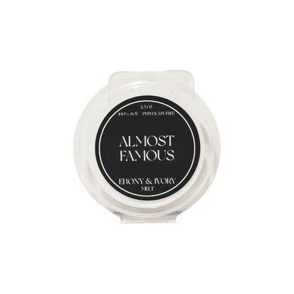 A clear 2.5oz clamshell scented soy wax melt with a black label named Almost Famous, on a white background, made by Ebony & Ivory Candle Co in Lethbridge, Alberta Canada