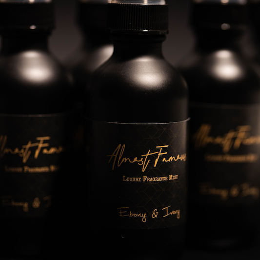 4 black 2oz mister bottles with black labels and gold lettering that reads "almost famous" sitting on a black background, made by ebony & ivory candle co in Lethbridge, Alberta, Canada