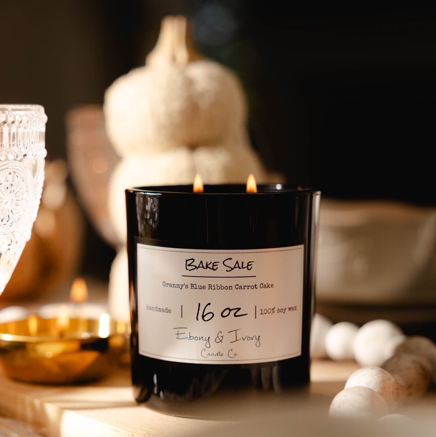 Bake Sale candle with a label on a table with pumpkins and decorative items.