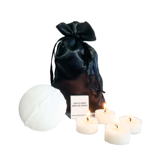 A black satin bag, a large bath bomb, a book of matches, and 4 tealights all together to make a bath buddy kit, on a white background, made by Ebony & Ivory Candle Co in Lethbridge, Alberta, Canada