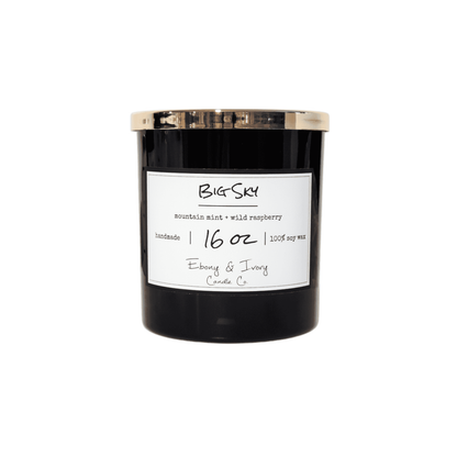 A black 16oz jar soy candle with a gold lid and a white label named Berried in the Pines, on a white background, made by Ebony & Ivory Candle Co in Lethbridge, Alberta, Canada