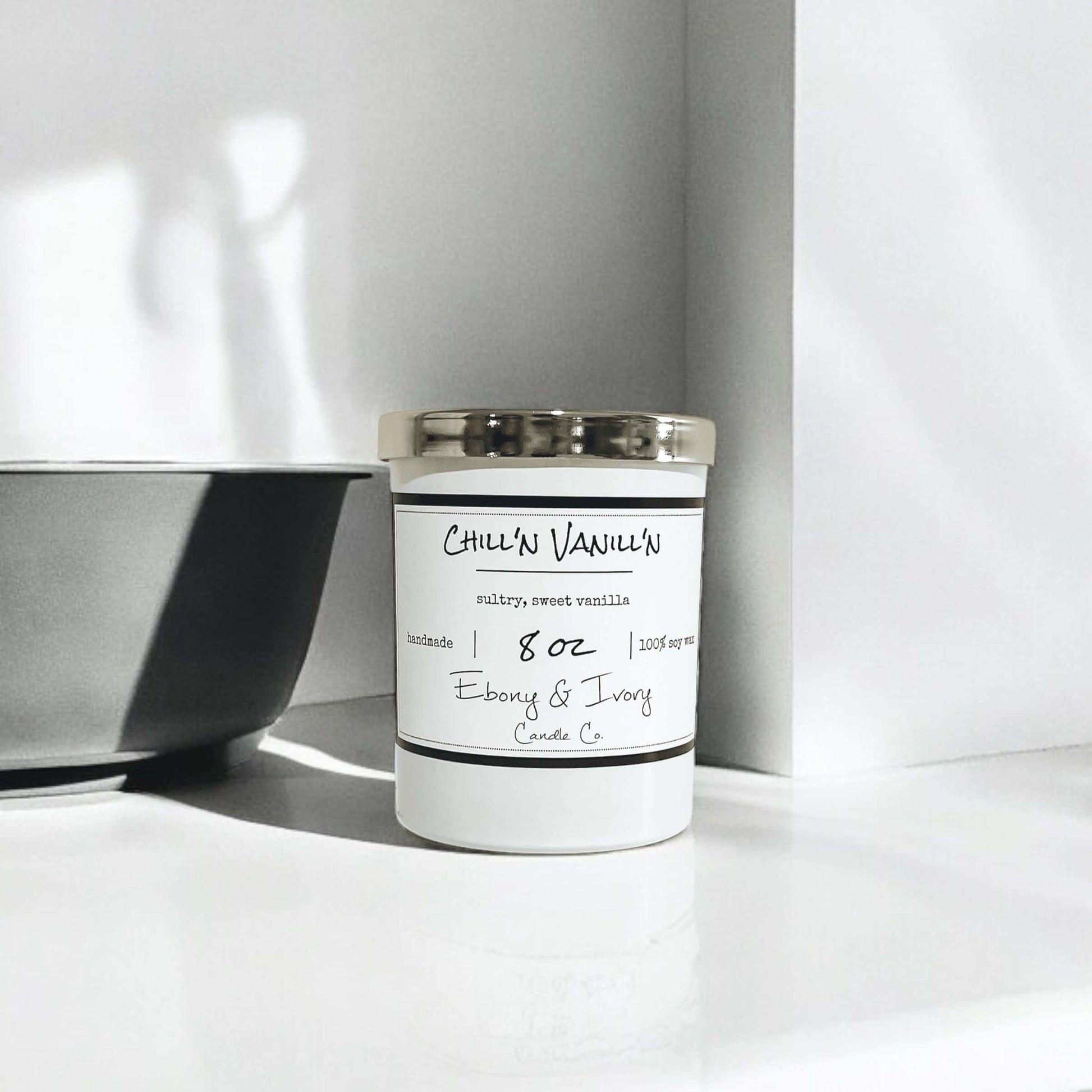 white 8oz jar soy candle with a gold lid and a white label named Chill'n Vanill'n, on a white counter with a grey bowl beside it, made by ebony & ivory candle co, in lethbridge, alberta, canada