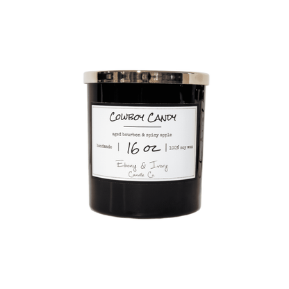 A black 16oz jar soy candle with a gold lid and a white label named Cowboy Candy on a white background, made by Ebony & Ivory Candle Co in Lethbridge, Alberta, Canada