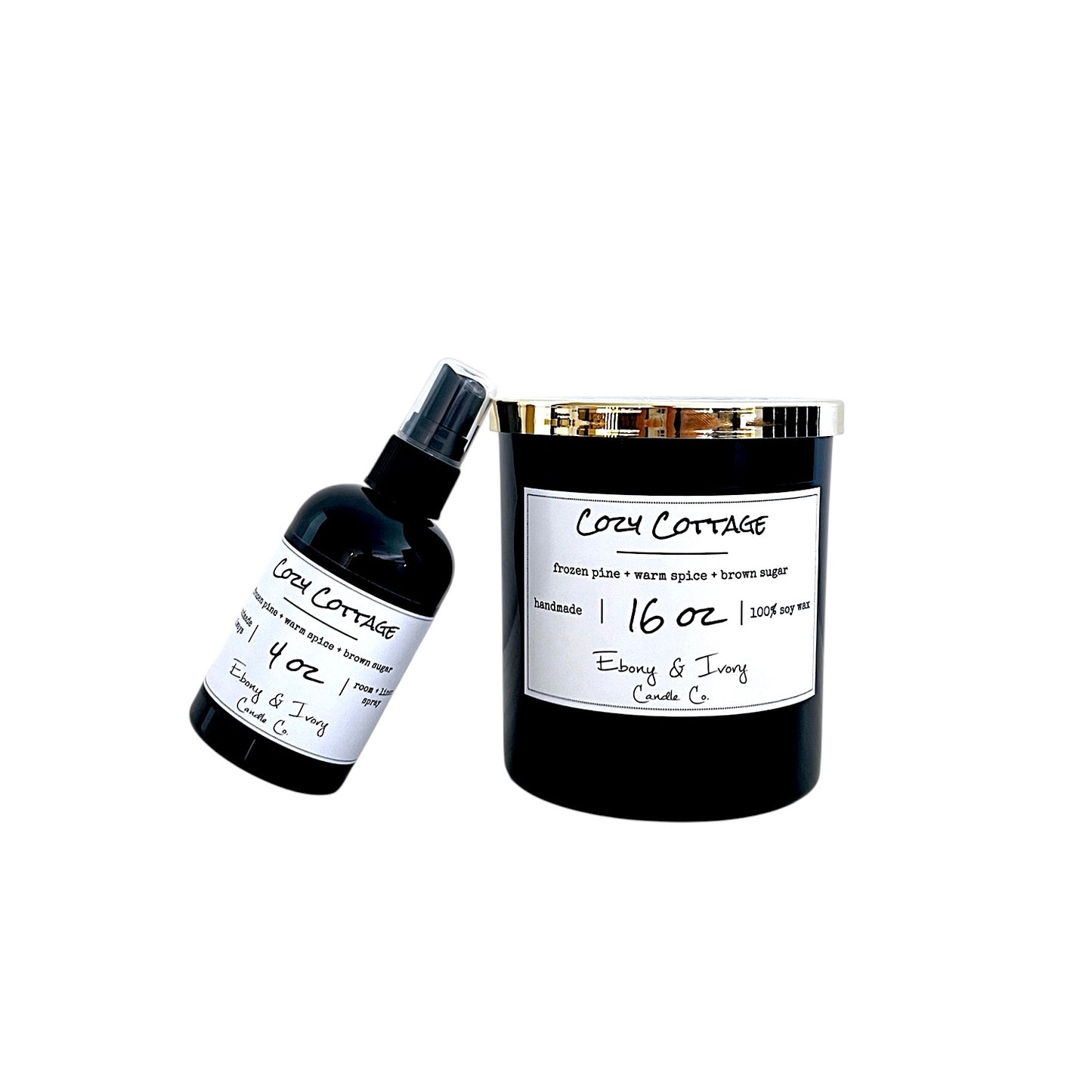 A black soy wax candle jar with a gold lid and a white label next to a small black spray bottle, both labeled 'Cozy Cottage' on a plain white background.