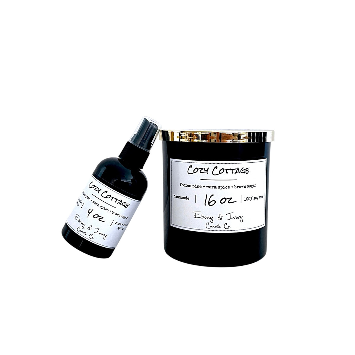 A black soy wax candle jar with a gold lid and a white label next to a small black spray bottle, both labeled 'Cozy Cottage' on a plain white background.