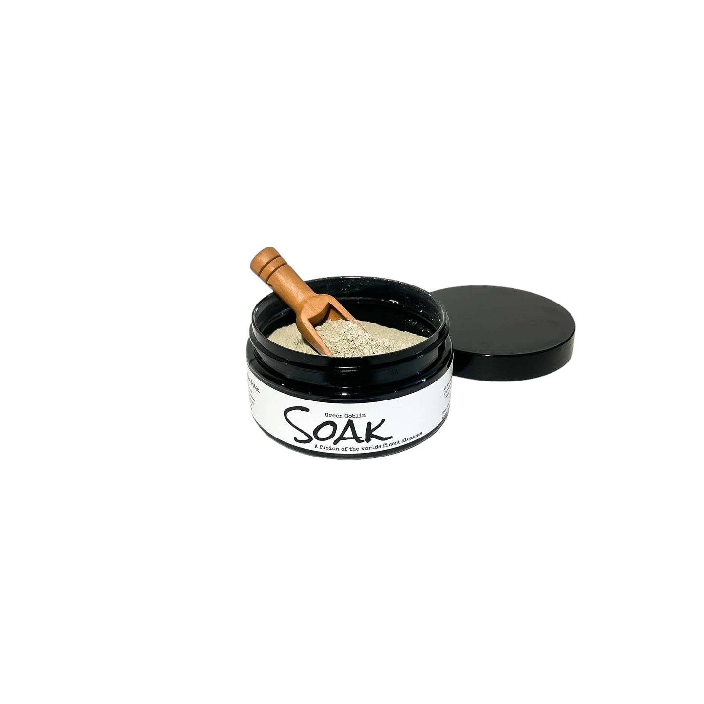 A 4oz round black jar with a white label named Green Goblin Clay Soak, with a wooden spoon, on a white background, made by Ebony & Ivory Candle Co in Lethbridge, Alberta, Canada