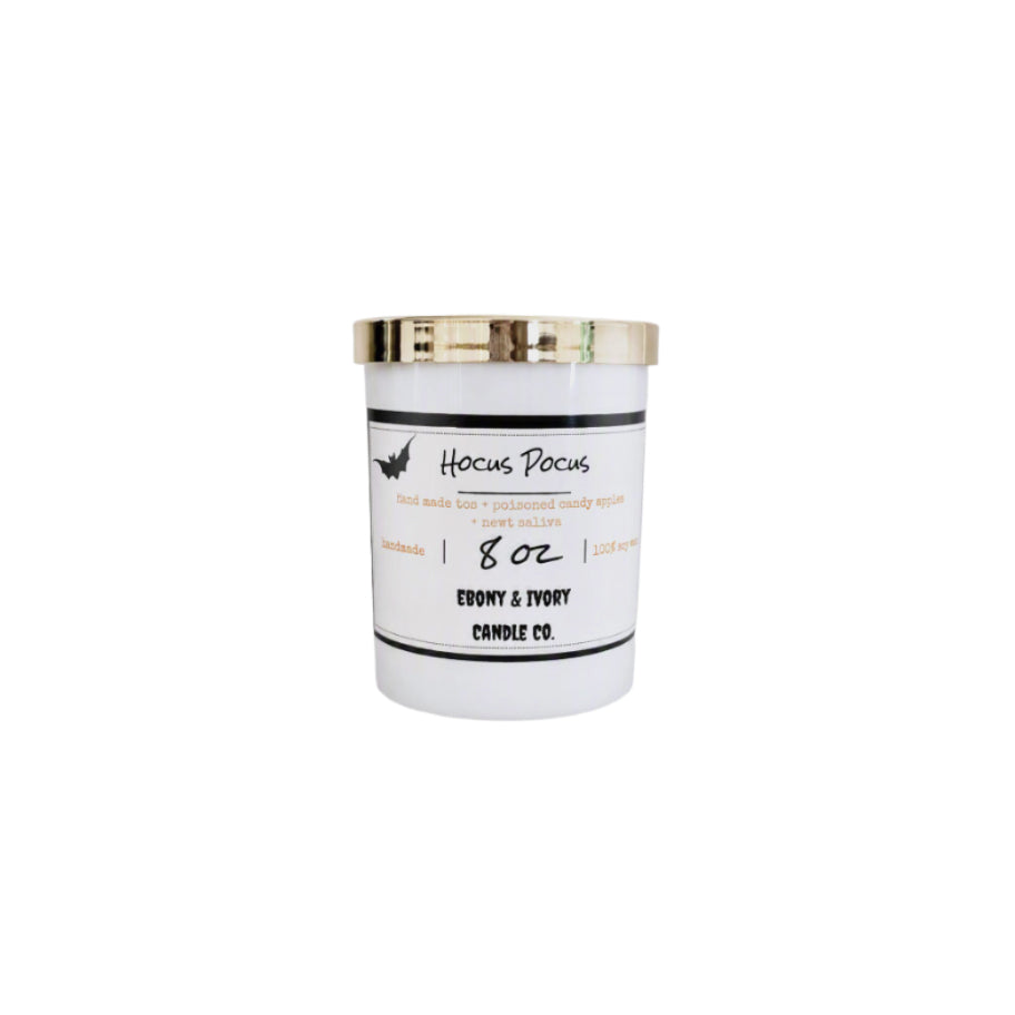 A white 8oz soy wax candle with a gold lid and a white label named "hocus pocus"