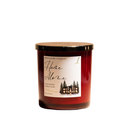 A red 16oz soy christmas candle with a gold lid and a white label named "home alone 1"