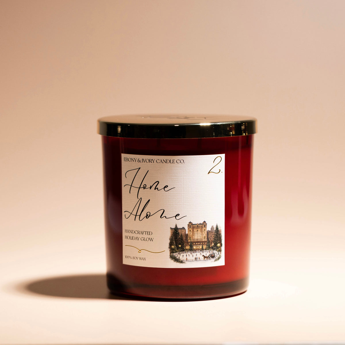 a red 16oz soy christmas candle with a gold lid and a white label named "home alone 2"
