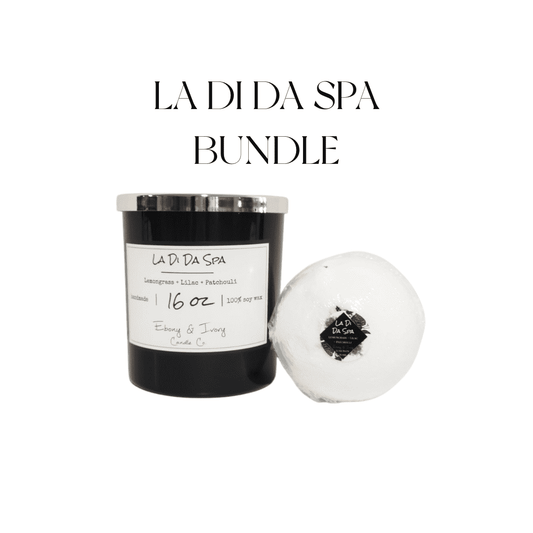 A black jar 16oz soy candle with a gold lid and a white label named La Di Da Spa, sitting next to a white bath bomb with hibiscus flowers on top and a round label named La Di Da Spa, on a white background, made by Ebony & Ivory Candle Co in Lethbridge, Alberta, Canada