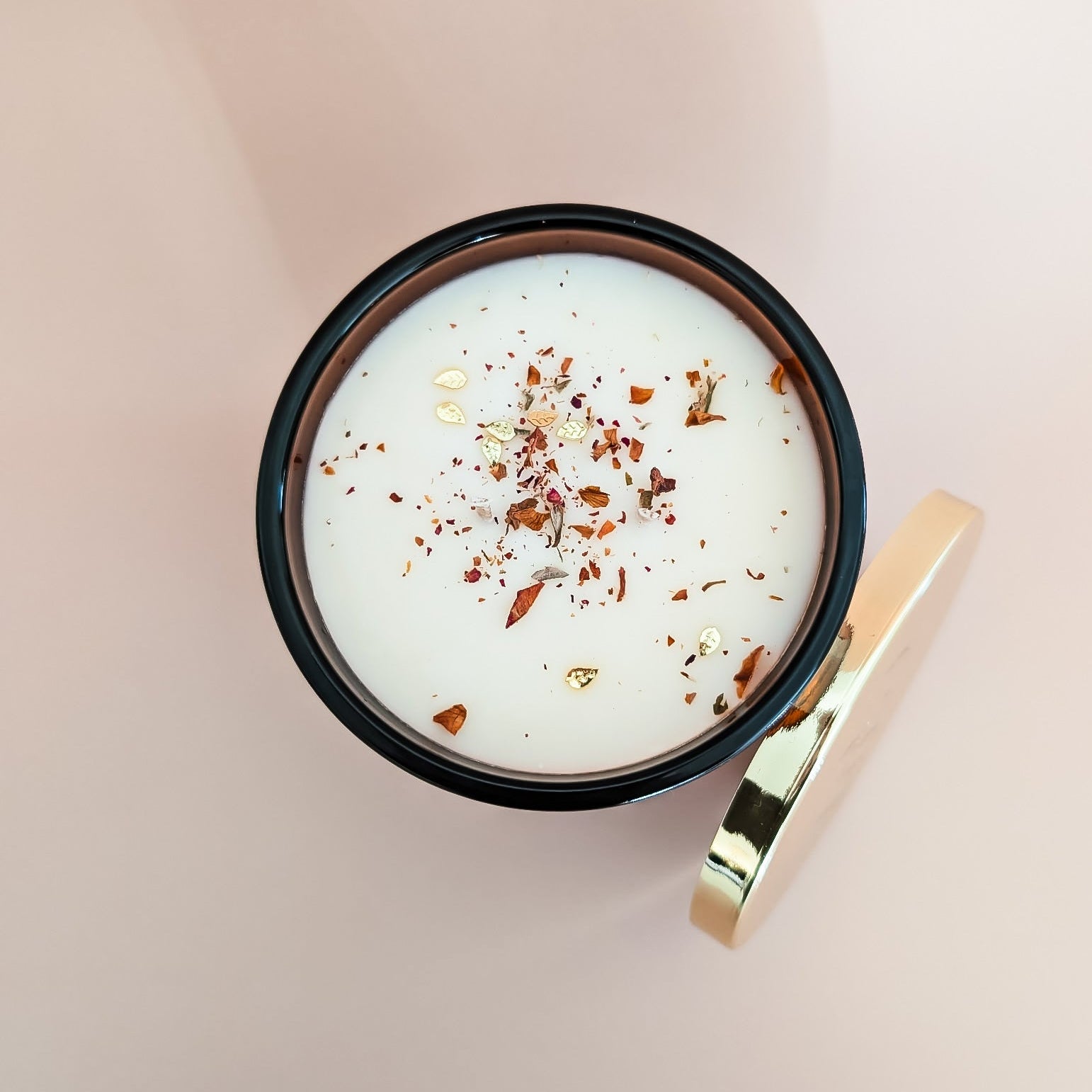 A top down view of an amber jar 16oz soy candle with dried rose petals and gold leaf glitters, and a gold lid on an ivory background, made by Ebony & Ivory Candle Co in Lethbridge, Alberta, Canada