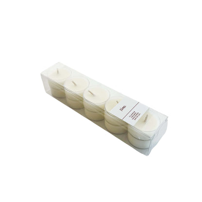 A clear box of 10 soy tea lights with a white label named Noel, on a white background, made by Ebony & Ivory Candle Co in Lethbridge, Alberta, Canada