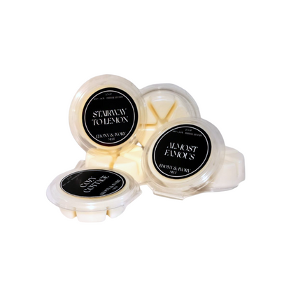 A pile of Ebony & Ivory Candle Co's 2.5oz clear clam shell luxx wax tarts on a white background, made in Lethbridge, Alberta, Canada