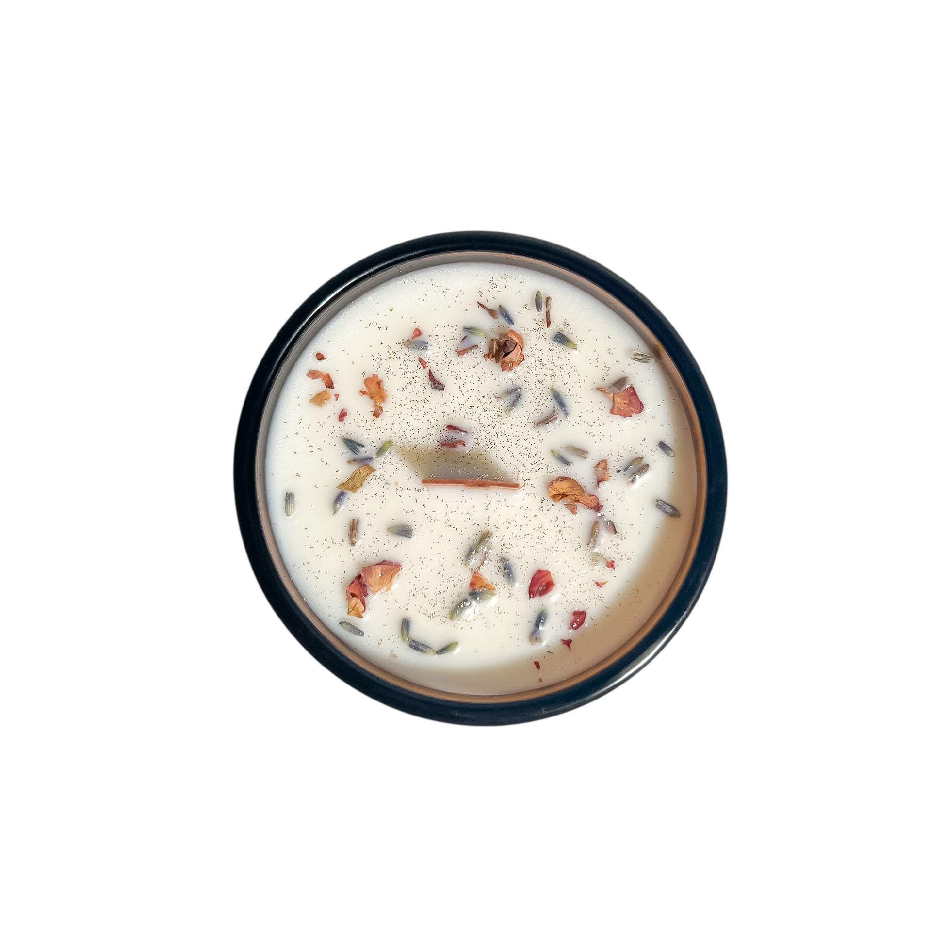 An amber jar 16oz soy wax candle with a wood wick, a gold lid, and an indigo label named "practical magic" on a white background topped with lavender buds and rose petals