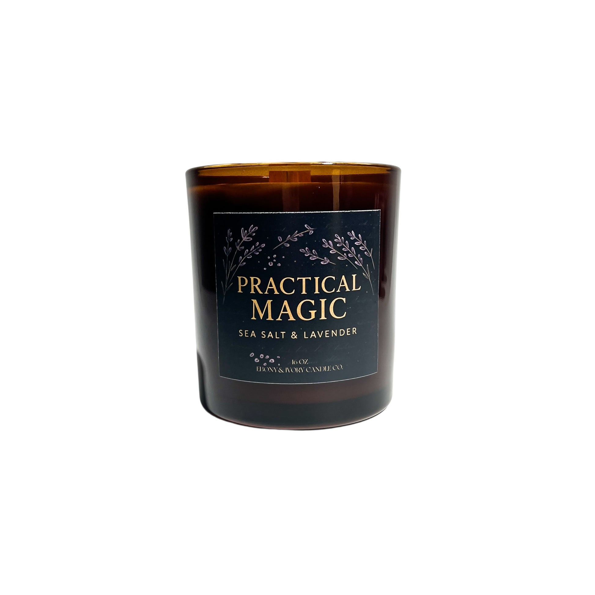 An amber jar 16oz soy wax candle with a wood wick, a gold lid, and an indigo label named "practical magic"
