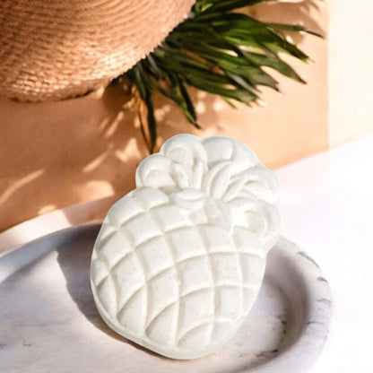 A pineapple shaped bath bomb with a sun hat in the background. Handmade healthy bath bomb 
