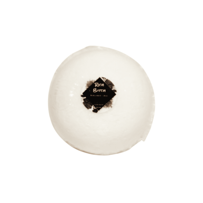 A white bath bomb with a round sticker label named Rich Bitch, on a white background, made by Ebony & Ivory Candle co in Lethbridge, Alberta, Canada