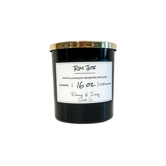 A black 16oz soy candle with a gold lid, labelled Rim Job, on a white background. Made in Lethbridge, Alberta, Canada