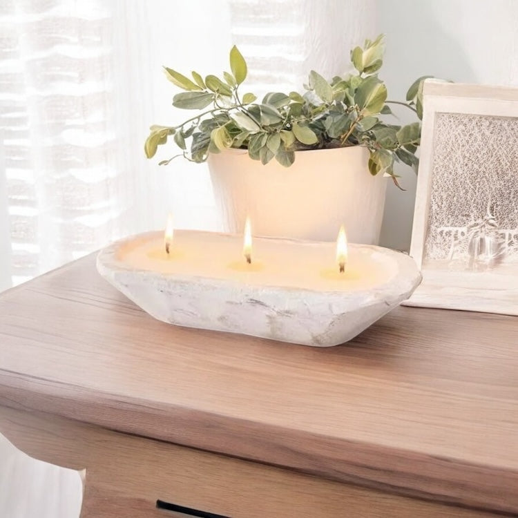A white short oval dough bowl soy candle on a light wood table with white sheer curtains and a potted plant, made by Ebony & Ivory Candle Co in Lethbridge, Alberta, Canada