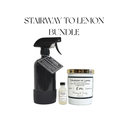 A black 16oz spray bottle of all purpose cleaner with a black rubber base and a black label named Stairway to Lemon, sitting next to a clear 2oz bottle of cleaner concentrate with a black cap and a white label, and a white 8oz jar soy candle with a gold lid and a white label. All sitting on a white background with black text above them that reads "Stairway to Lemon Bundle." made by Ebony & Ivory Candle Co in Lethbridge, Alberta, Canada