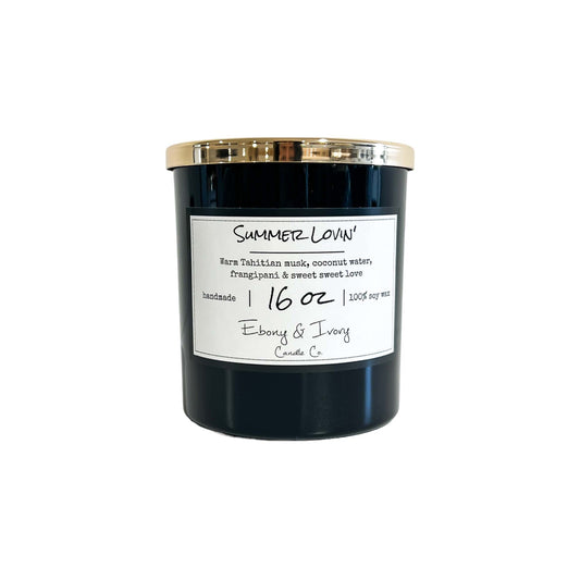 A black 16oz soy candle with a gold lid labelled Summer Lovin, on a white background. Made in Lethbridge, Alberta, Canada